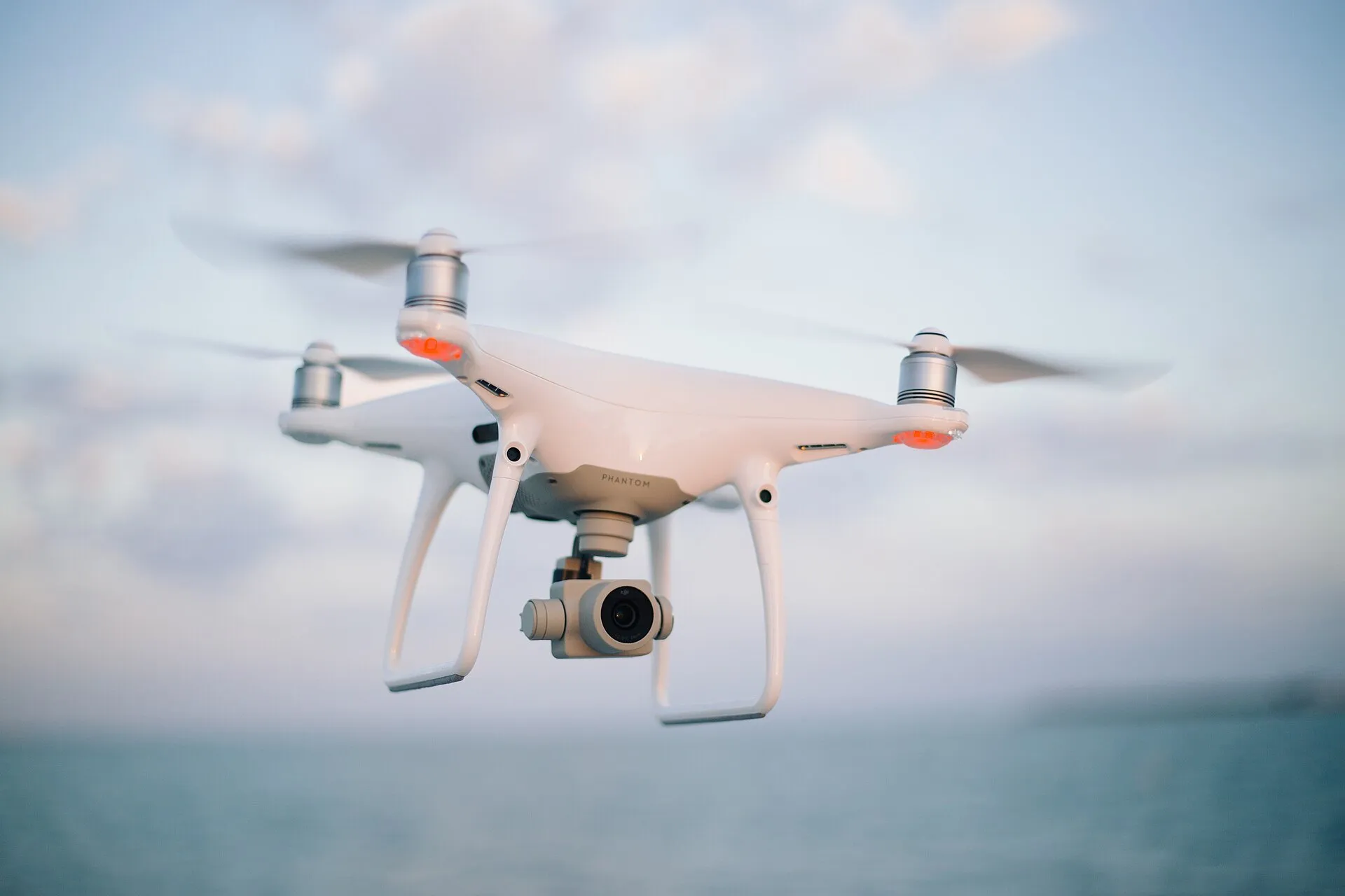 Dron cuadricóptero blanco volando sobre el mar