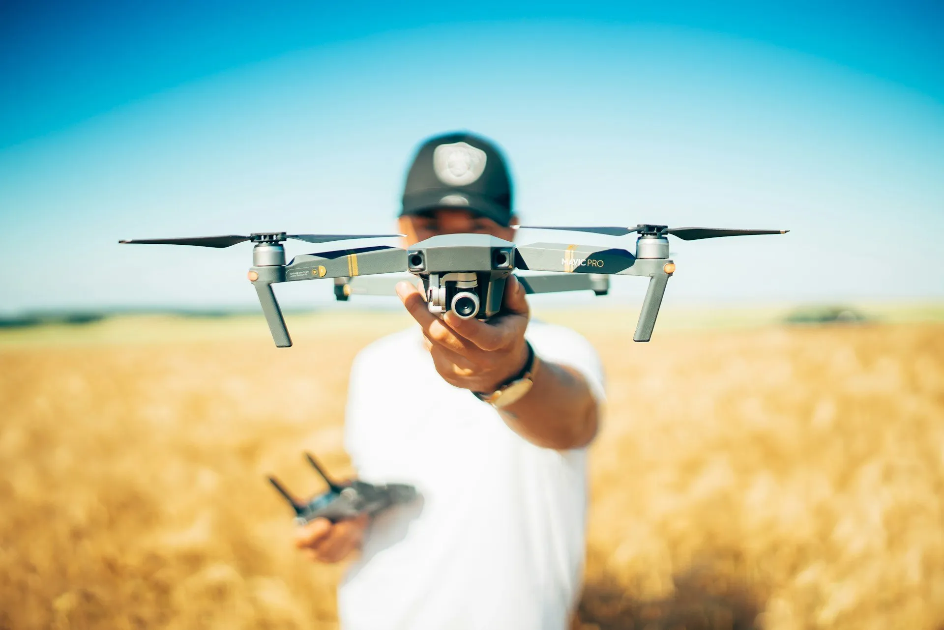 Piloto sosteniendo un dron en un campo de trigo
