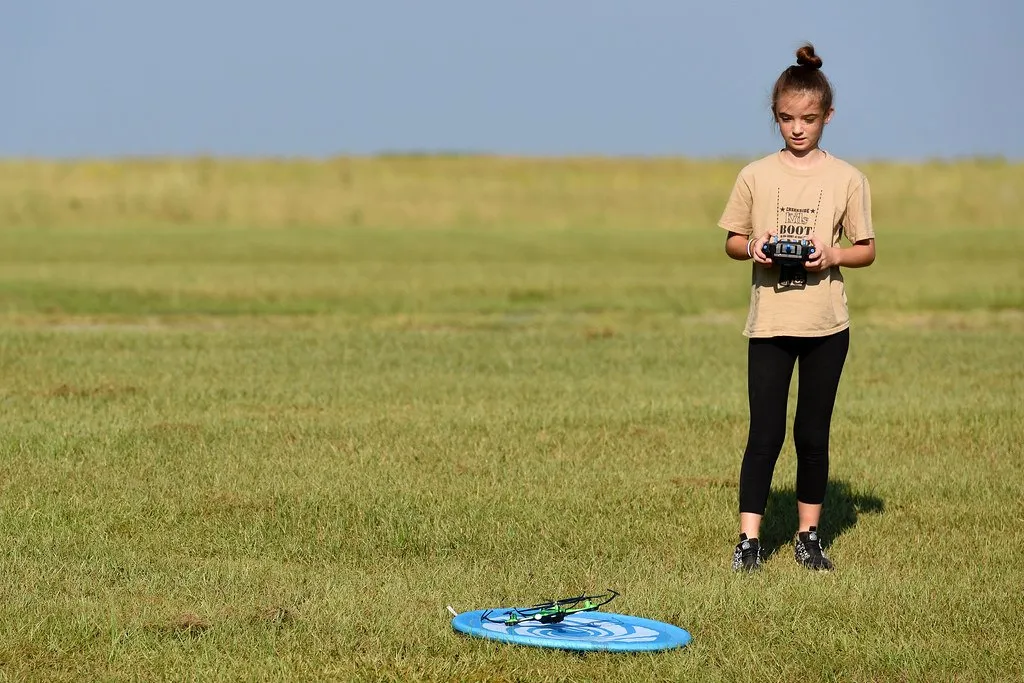 Niña piloteando un dron en un campo abierto